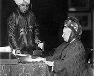 Queen Victoria at her desk, assisted by her servant Abdul Karim, the ‘Munshi’. Date: c. 1885